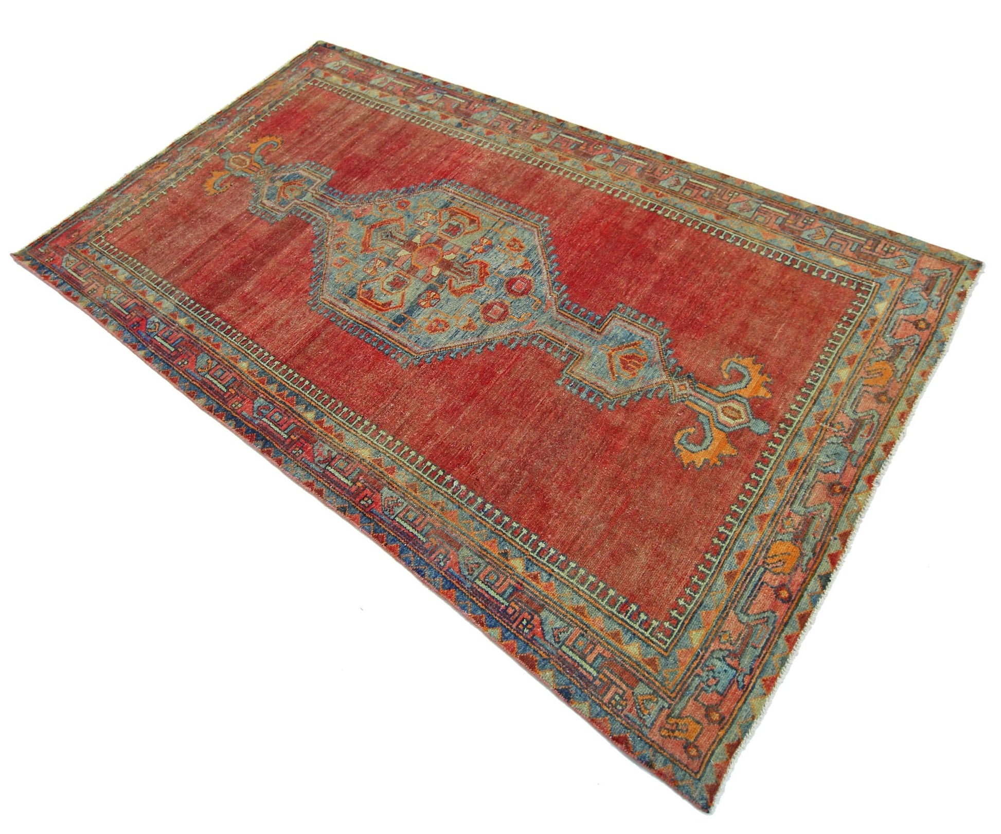 A vintage Persian rug featuring a central geometric medallion on a red field with blue accents.