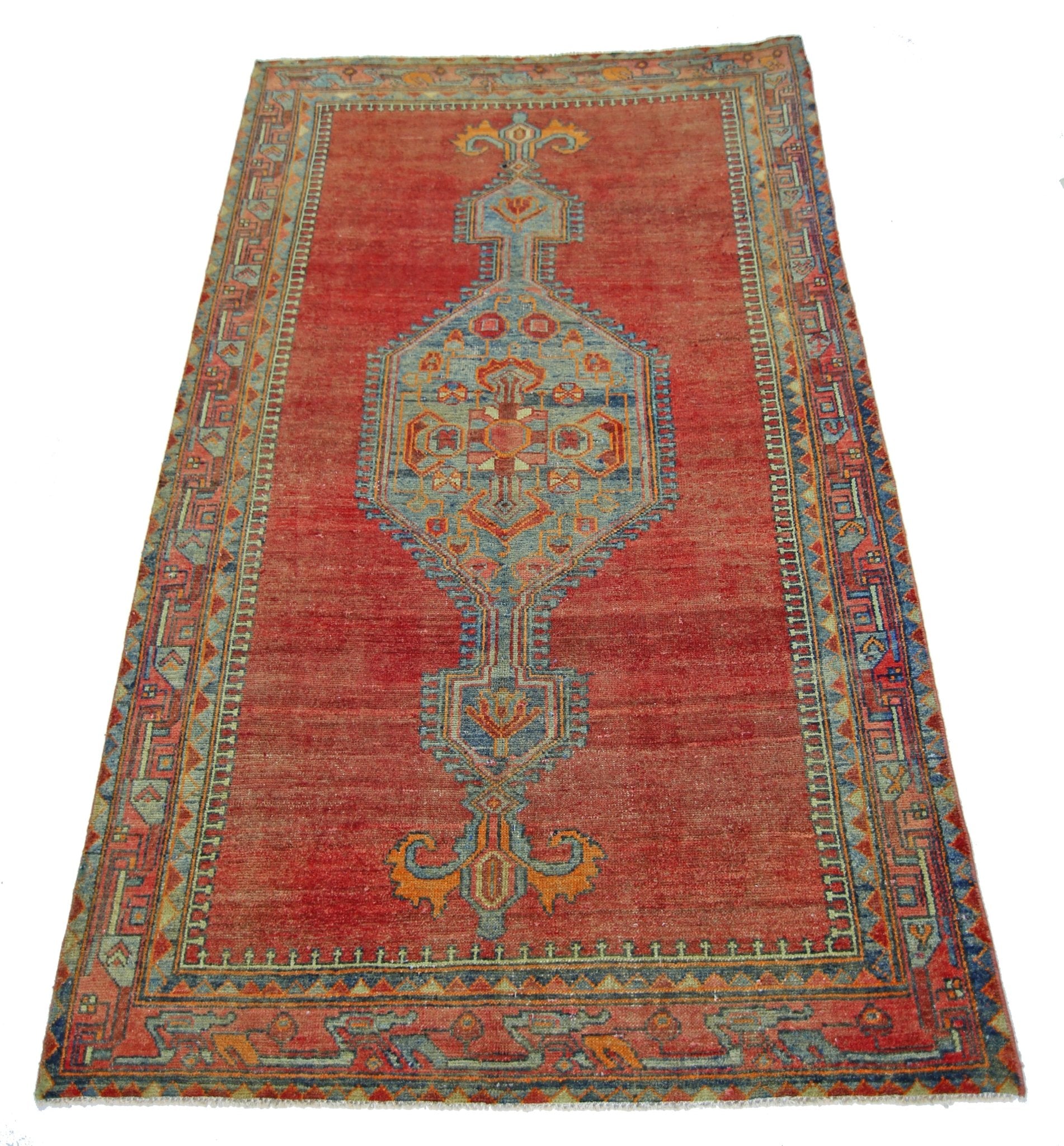 A vintage handmade Persian rug featuring a central blue medallion on a red field.