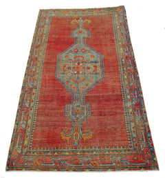 A vintage handmade Persian rug featuring a central blue medallion on a red field.