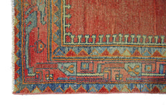 A corner detail of a vintage Persian rug featuring geometric patterns in red, blue, and green.