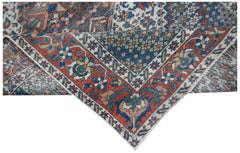 Vintage Persian rug with intricate floral patterns in red, blue, and cream.