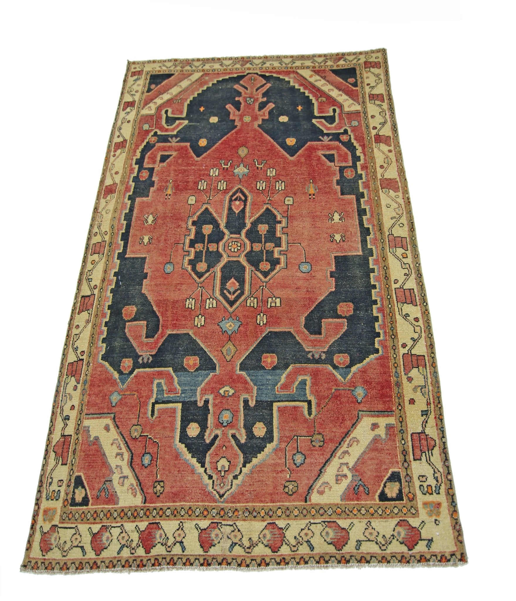 A vintage handmade Persian rug featuring a geometric medallion pattern in red, blue, and cream.
