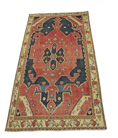 A vintage handmade Persian rug featuring a geometric medallion pattern in red, blue, and cream.