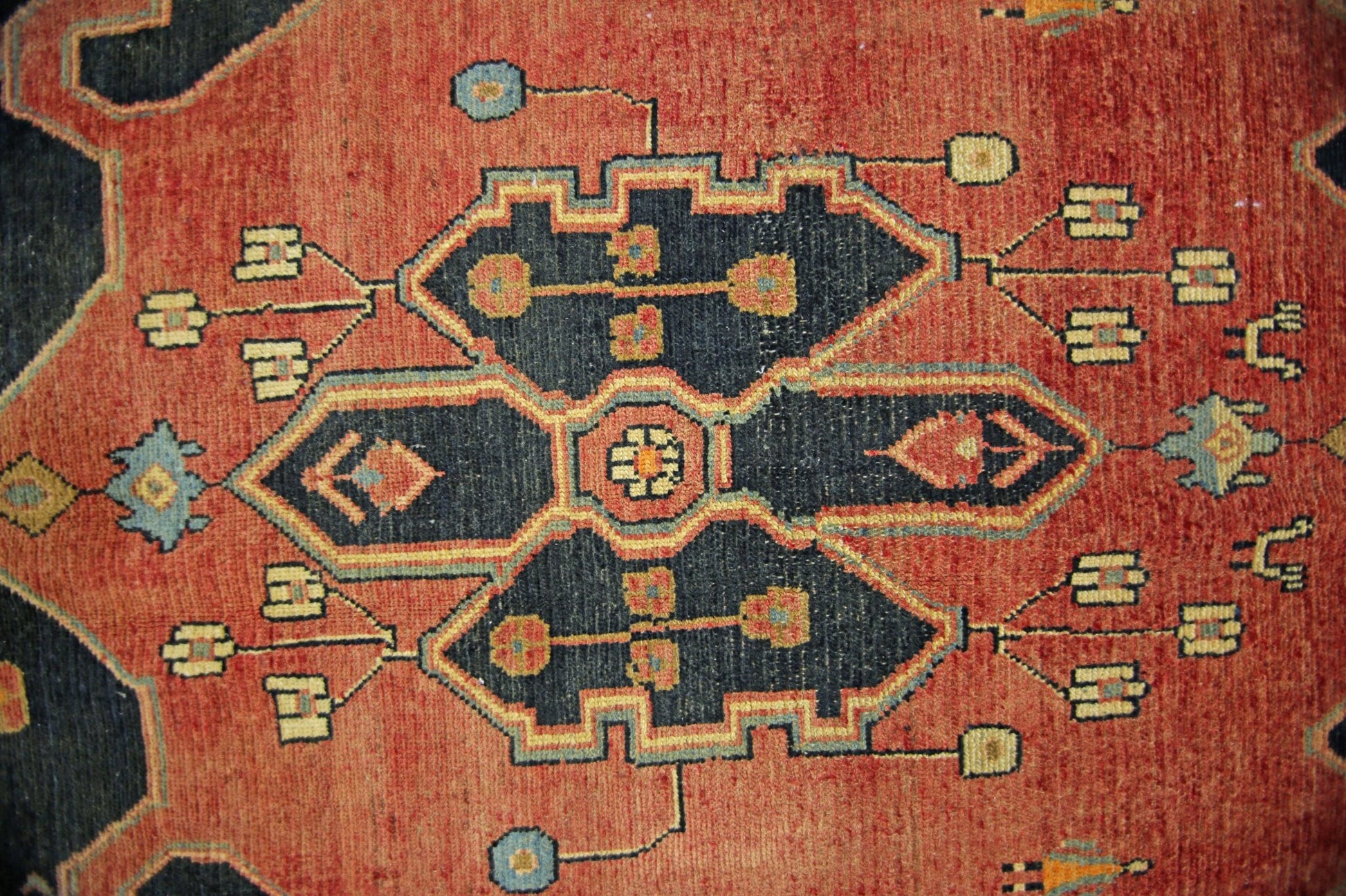 A vintage Persian rug featuring a central dark blue geometric medallion on a red field.