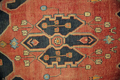 A vintage Persian rug featuring a central dark blue geometric medallion on a red field.