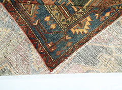 A corner of a vintage Persian rug is folded over to show its intricate blue and red wool pattern.