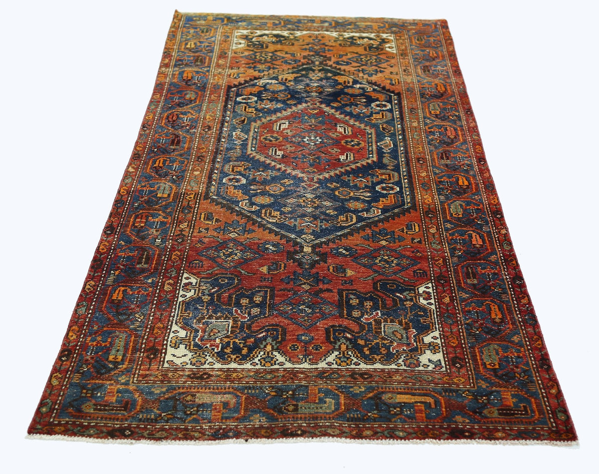 A vintage Persian rug featuring a central blue medallion and intricate geometric patterns in red.