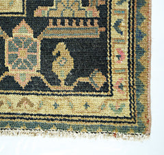 A vintage Persian rug featuring a black field with intricate geometric patterns and a tan border.
