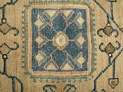 A vintage Persian rug featuring a central blue geometric medallion with intricate floral patterns.