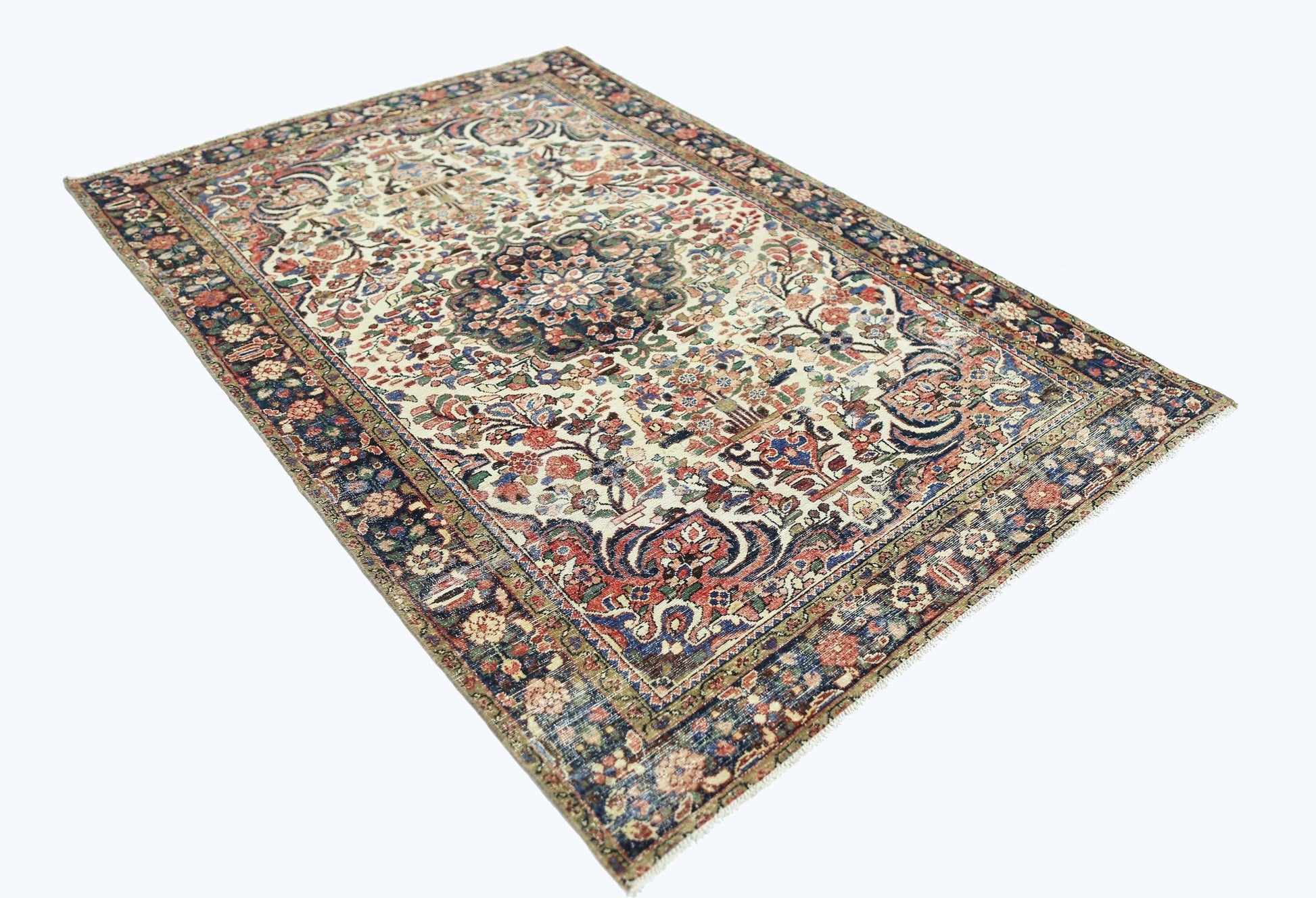 A vintage handmade Persian rug featuring a central floral medallion on a cream field.