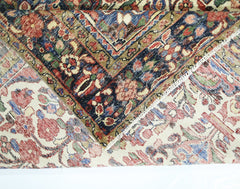 A vintage handmade Persian rug with a floral pattern folded to show its wool pile and cotton base.