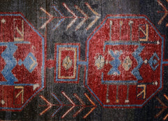 A vintage Persian rug featuring geometric red medallions and arrow motifs on a dark background.