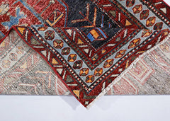A vintage handmade Persian rug with a geometric pattern in red, blue, and cream wool.