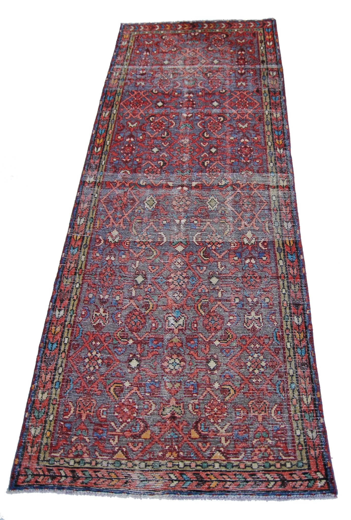 A vintage handmade Persian runner rug featuring a geometric pattern in red, blue, and cream tones.