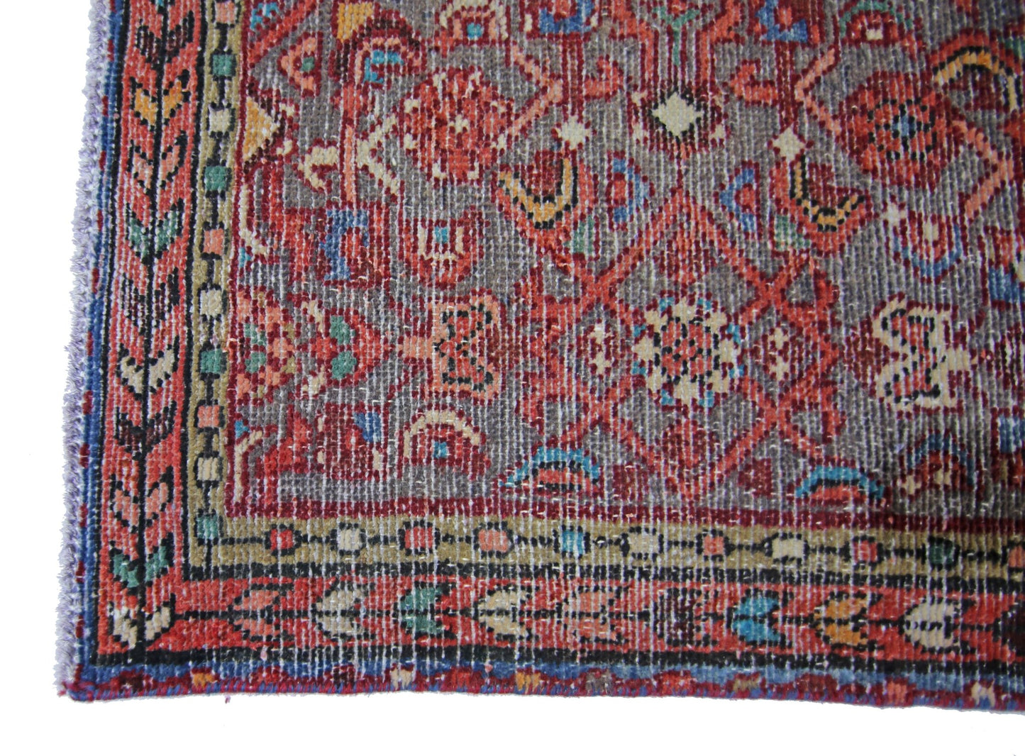A vintage handmade Persian rug featuring a geometric red and grey pattern with a decorative border.