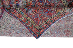 A folded vintage Persian rug featuring intricate red, blue, and yellow geometric patterns.