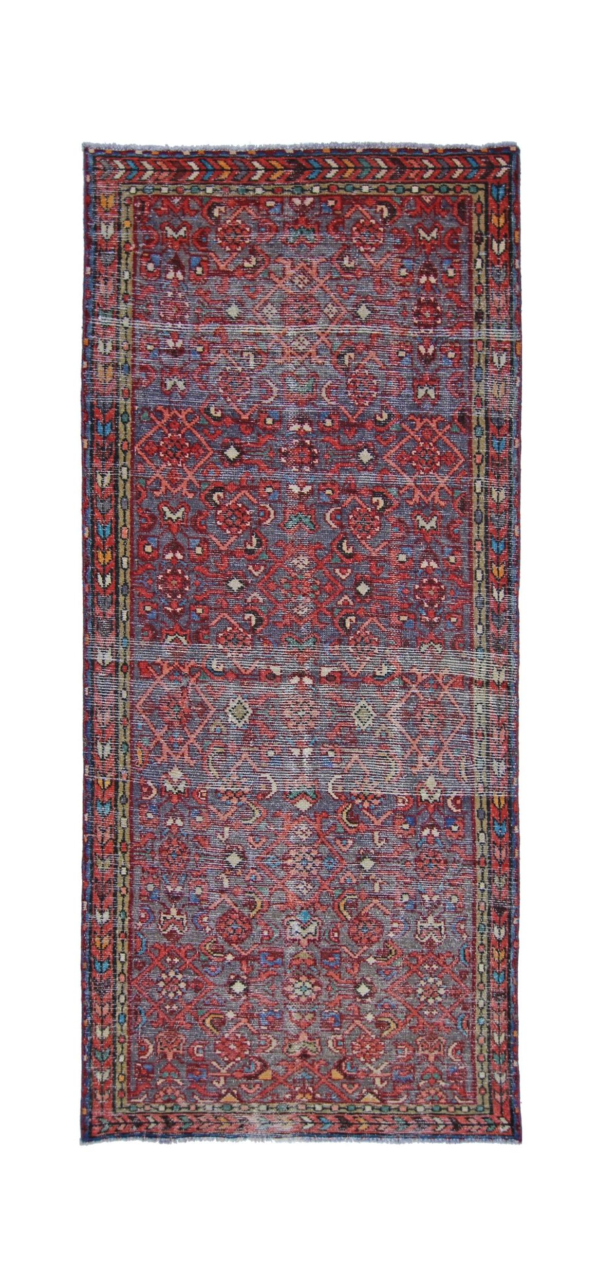 A rectangular vintage Persian rug featuring a geometric red and blue pattern with a floral border.