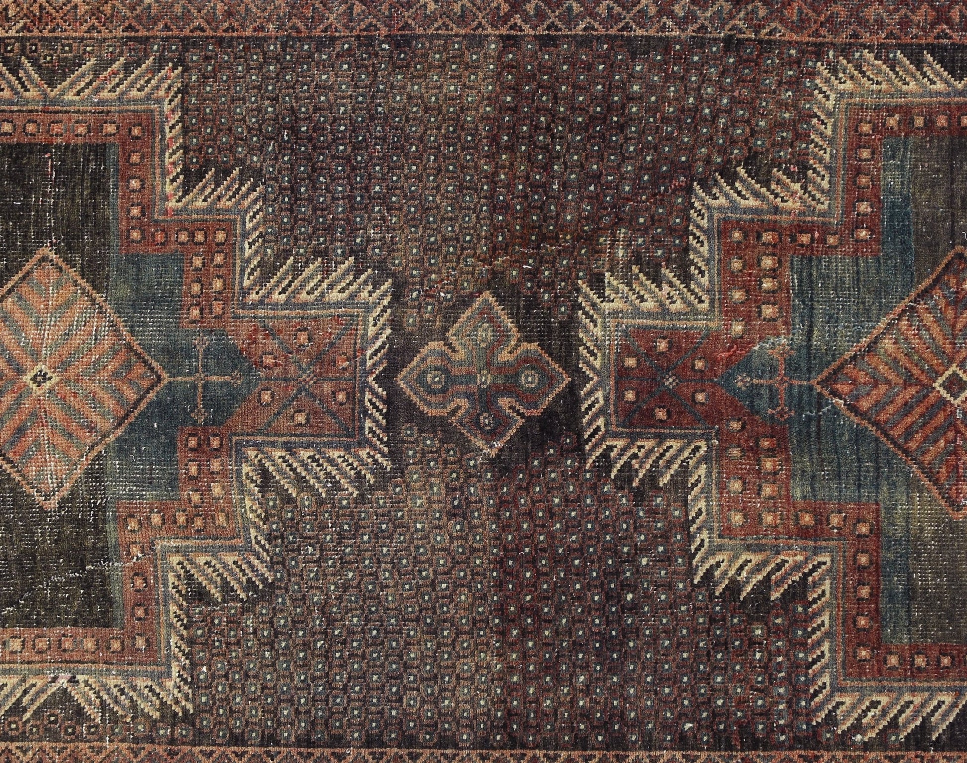 A vintage Persian rug featuring a geometric pattern in deep red, blue, and brown tones.
