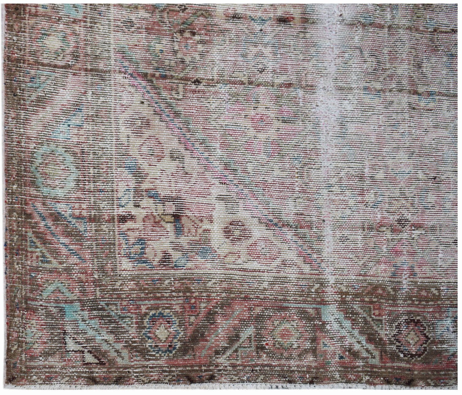 A handwoven vintage Persian rug featuring a faded floral pattern in muted pink, blue, and brown.