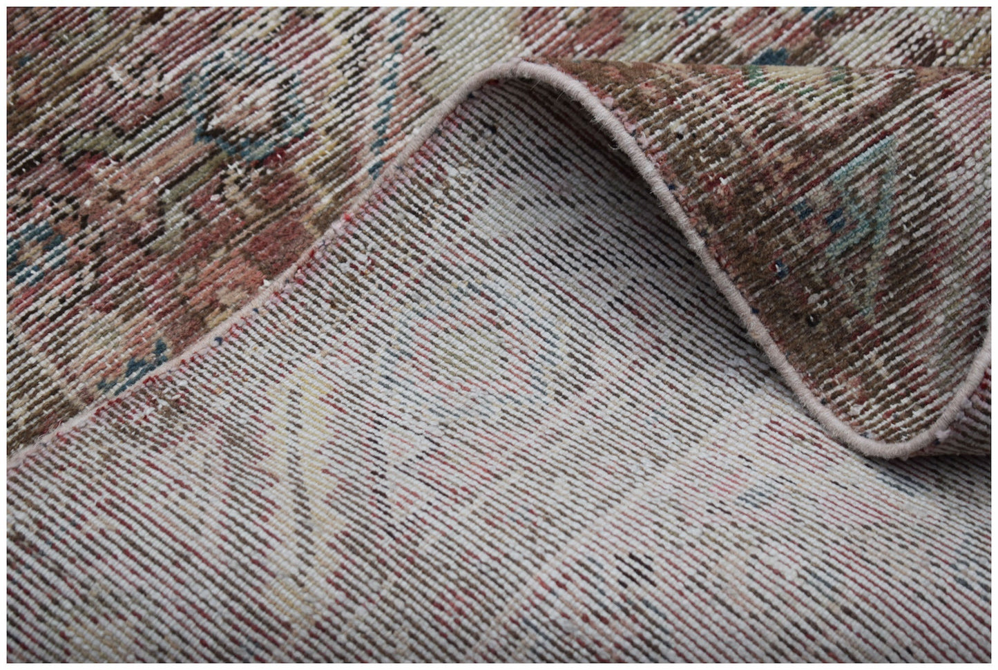 A close-up view of a handwoven vintage Persian rug showing its worn texture and cotton backing.
