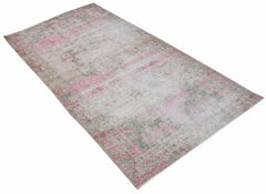 A vintage handwoven Persian rug featuring a distressed pattern in shades of pink and grey.