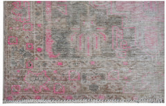 A vintage Persian rug featuring a distressed pattern in shades of brown, grey, and vibrant pink.