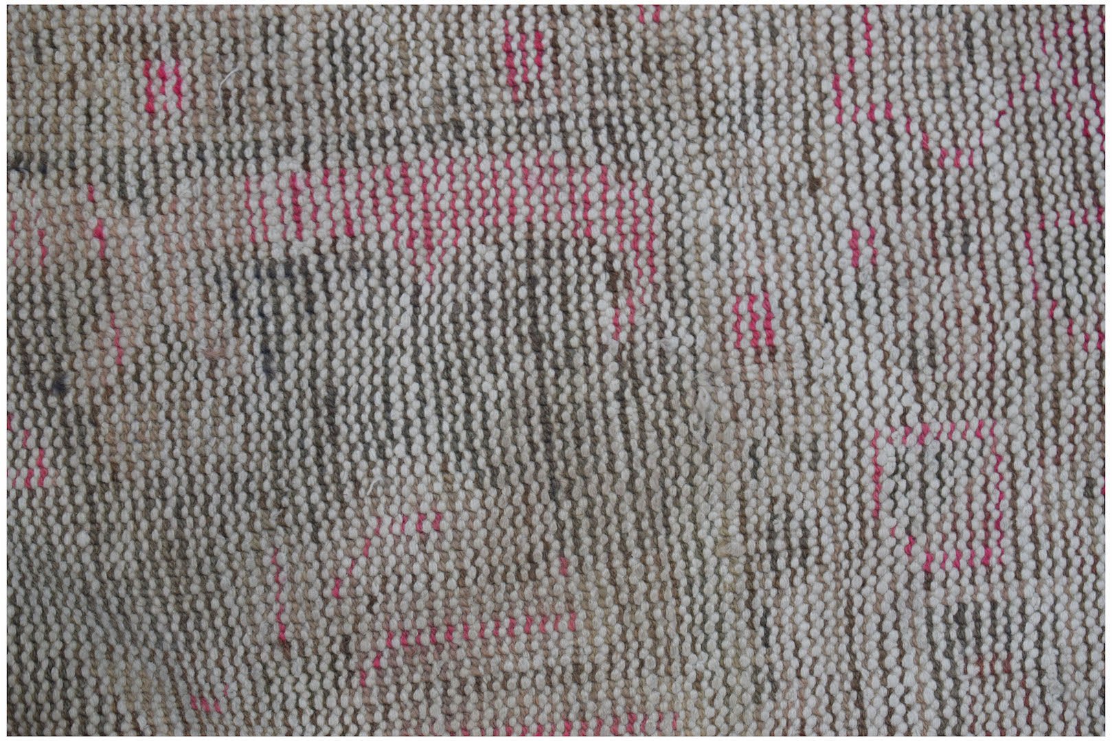 A close-up of a vintage Persian rug featuring a distressed, handwoven wool texture in neutral tones.
