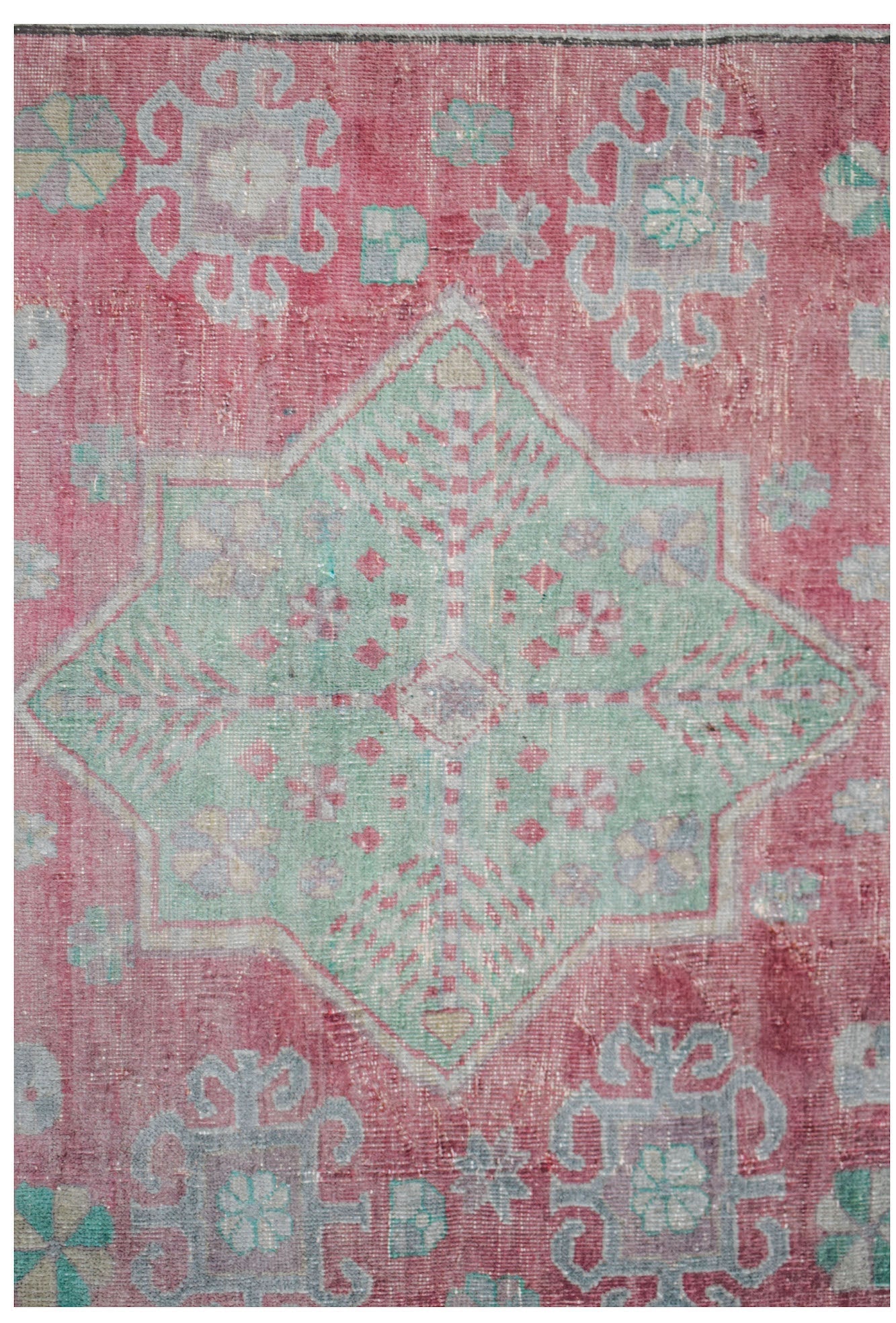 A vintage handwoven Persian rug featuring a central green star medallion on a faded red background.