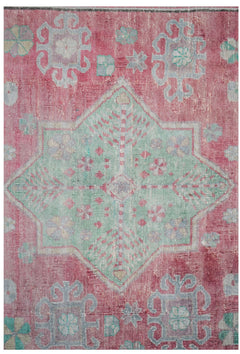 A vintage handwoven Persian rug featuring a central green star medallion on a faded red background.