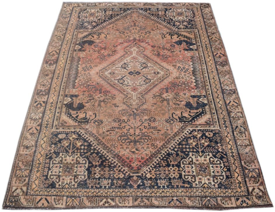 A vintage handmade Persian wool rug featuring a central diamond medallion in muted orange and navy.