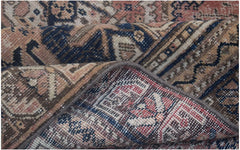 A folded vintage Persian wool rug featuring intricate tribal patterns in muted earth tones.