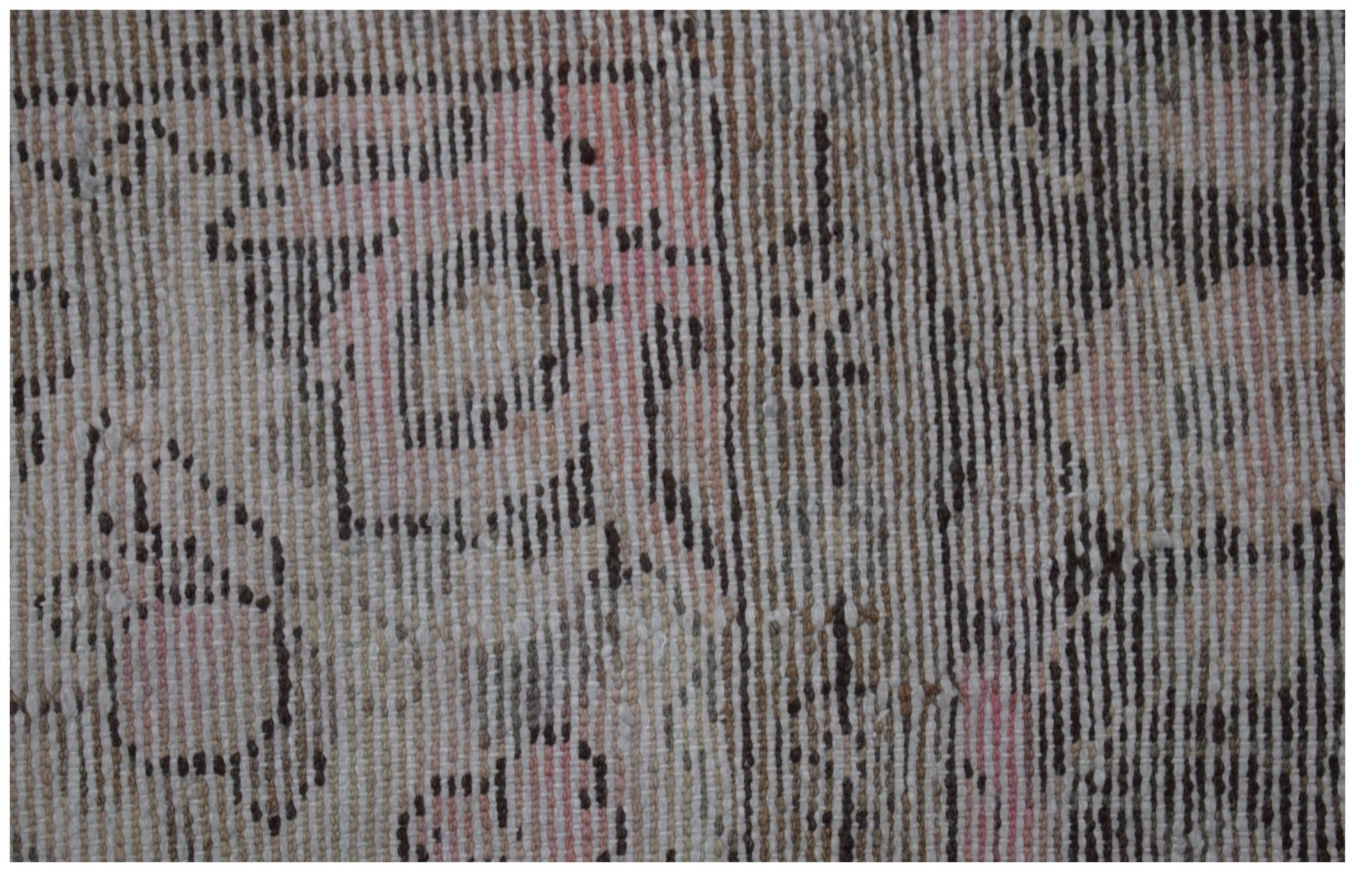 A close-up of a vintage Persian rug featuring a faded geometric pattern in pink, brown, and cream.