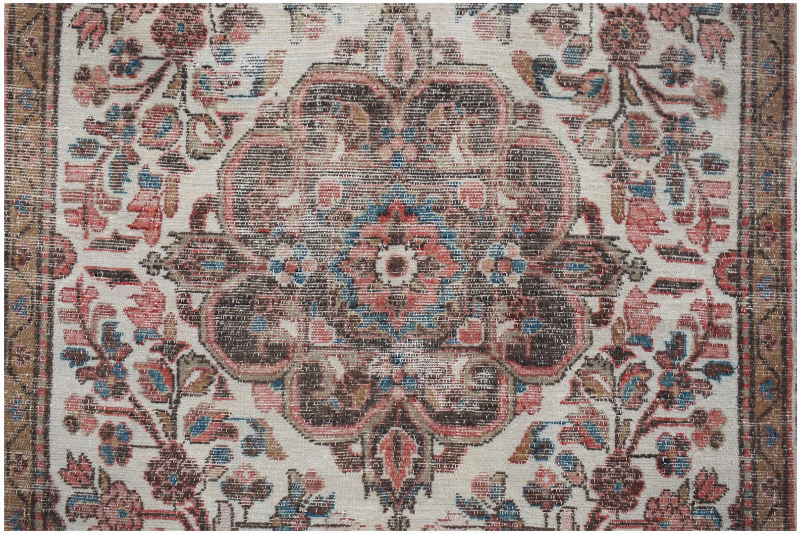 A vintage handwoven Persian rug featuring a central floral medallion in muted red and brown tones.