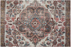 A vintage handwoven Persian rug featuring a central floral medallion in muted red and brown tones.