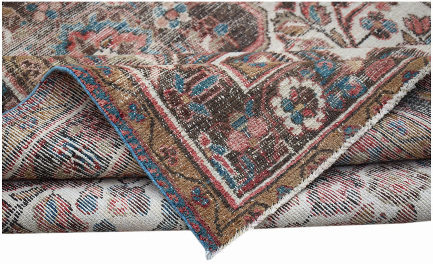 A folded vintage Persian rug featuring intricate floral patterns in muted red, blue, and brown.