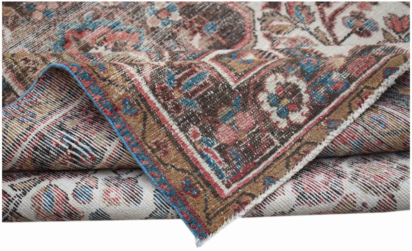A folded vintage Persian rug featuring intricate floral patterns in muted red, blue, and brown.
