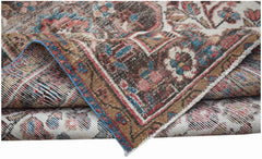A folded vintage Persian rug featuring intricate floral patterns in muted red, blue, and brown.