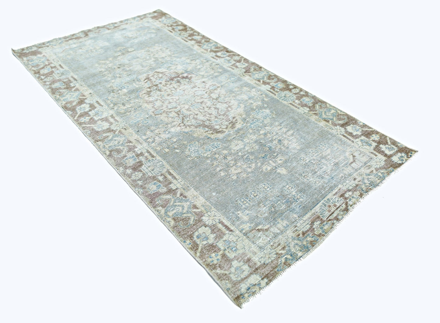 A vintage Persian rug featuring a faded blue and brown floral pattern on a light background.