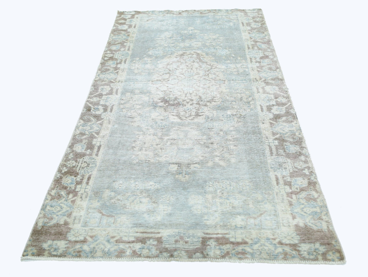 A vintage Persian rug featuring a faded blue and beige floral medallion pattern.