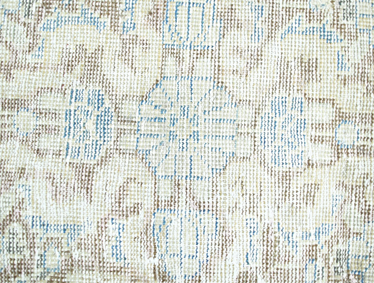 A close-up view of a vintage Persian rug featuring a faded floral pattern in blue and brown tones.