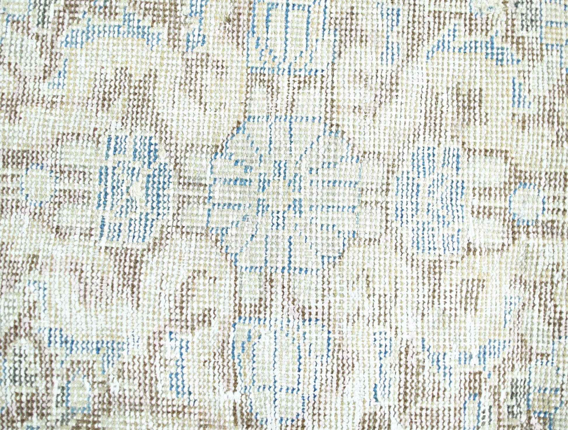 A close-up view of a vintage Persian rug featuring a faded floral pattern in blue and brown tones.