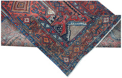 A handwoven vintage Persian rug featuring intricate geometric patterns in red, blue, and brown.