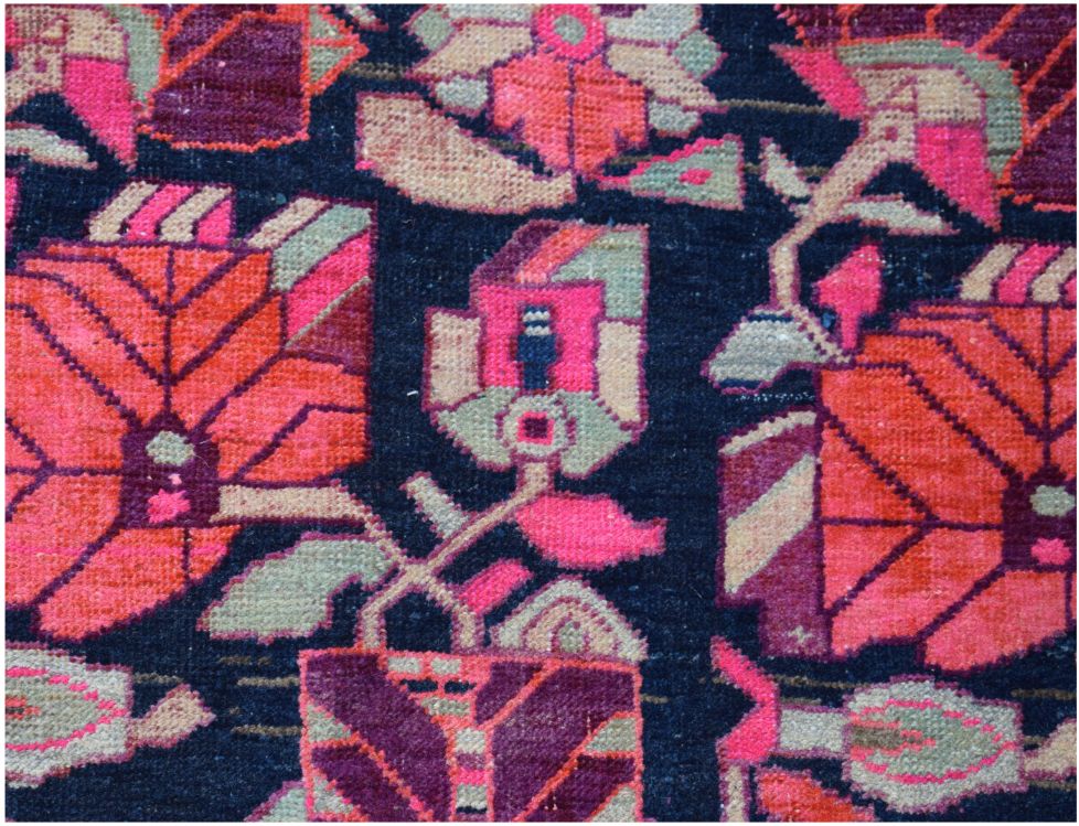 A vintage Persian rug featuring a dark blue background with vibrant pink and orange floral patterns.