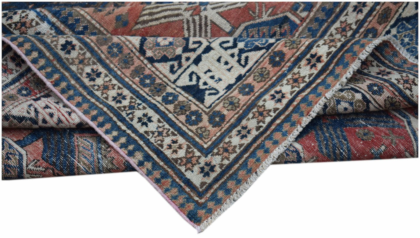 A handwoven vintage Persian rug featuring a geometric pattern in shades of blue, red, and cream.