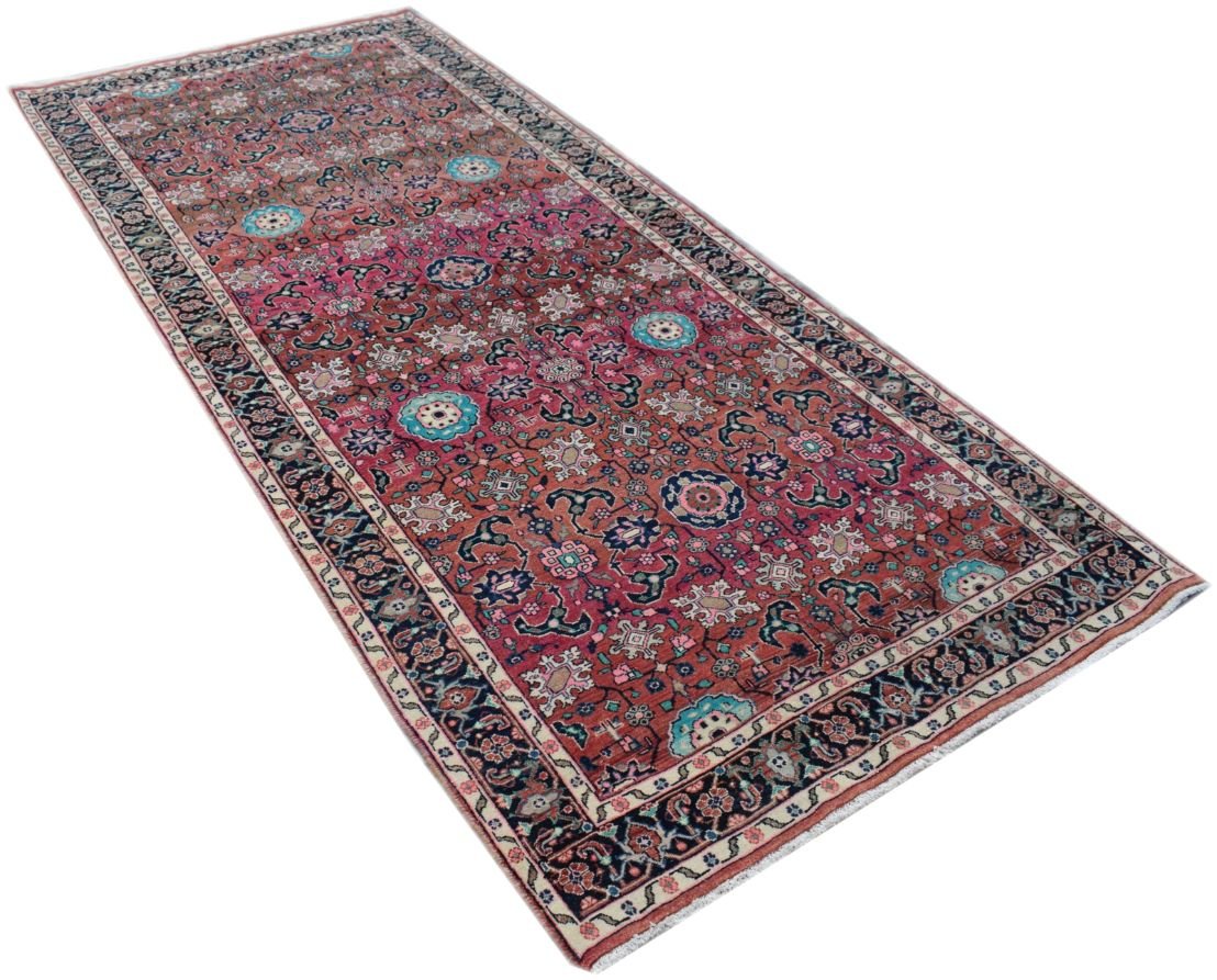A rectangular vintage Persian rug featuring a floral pattern in shades of red, blue, and cream.
