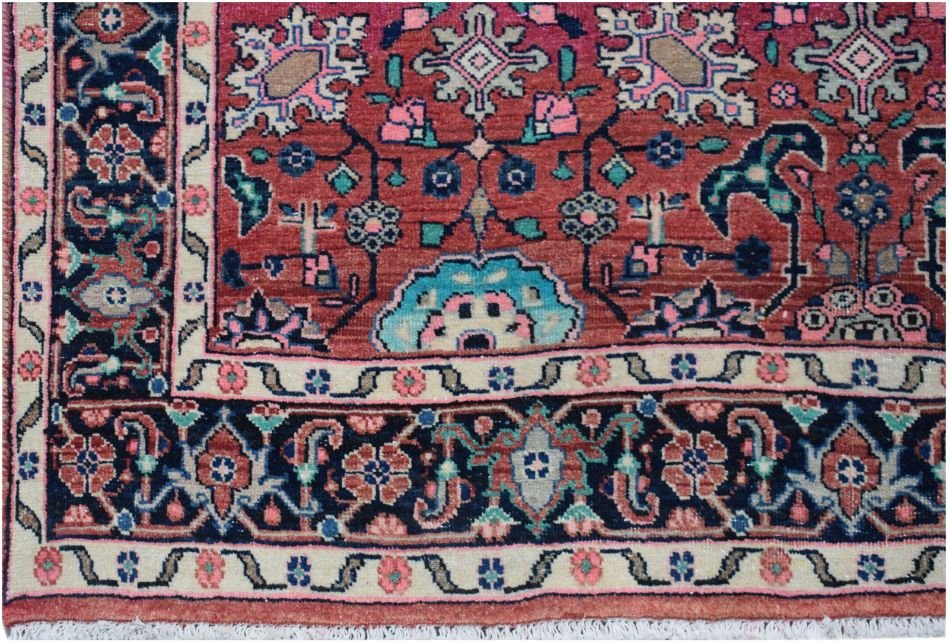 A vintage Persian rug featuring a red field with intricate floral patterns and a dark blue border.