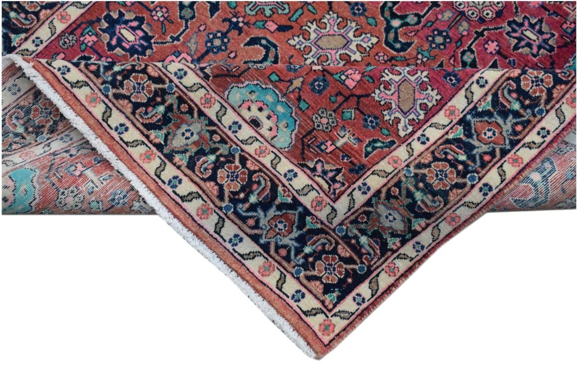 A folded vintage Persian wool rug featuring a traditional floral pattern in red and blue tones.