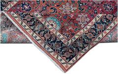 A folded vintage Persian wool rug featuring a traditional floral pattern in red and blue tones.