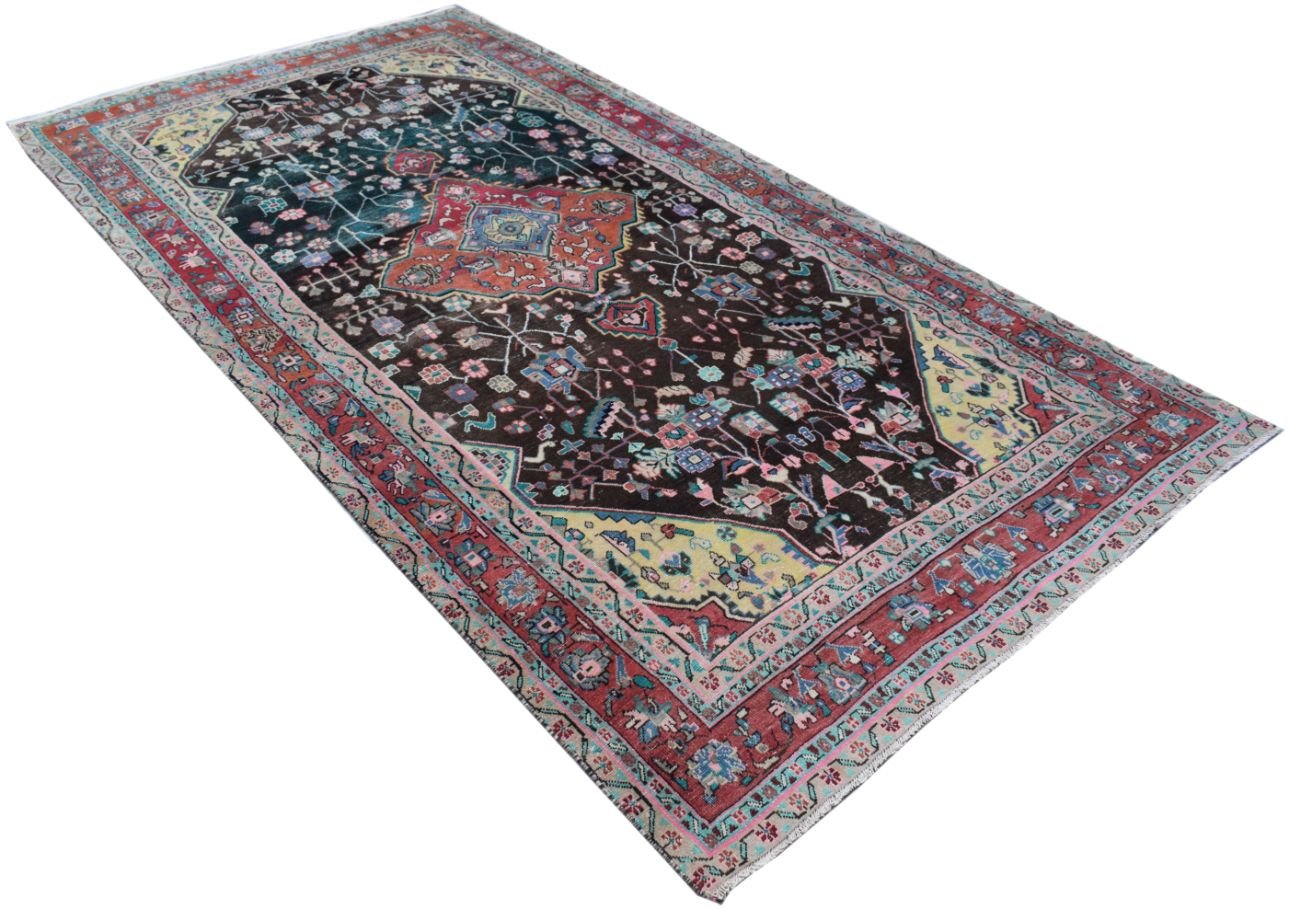 A rectangular handmade Persian rug featuring a dark field with floral patterns and colorful borders.