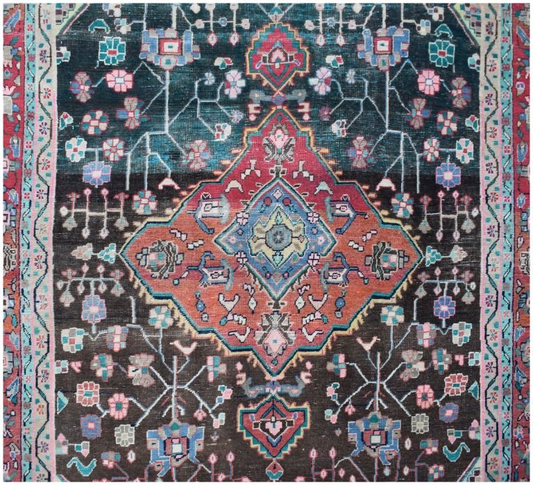 A vintage handmade Persian wool rug featuring a central geometric medallion on a dark field.